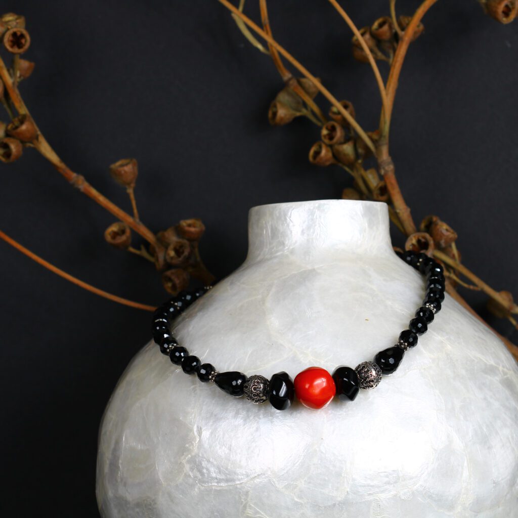 A black beaded chain with the touch of red stone