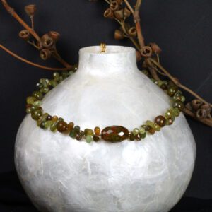 A white vase with some green beads on it