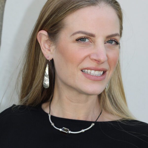 A woman wearing a black shirt and silver jewelry.