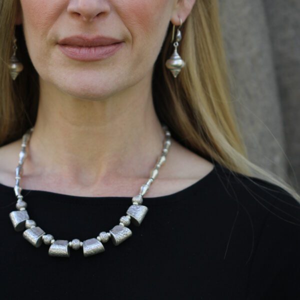 A woman wearing a silver necklace and earrings.