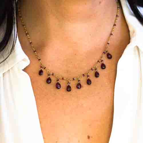 Delicate gold necklace with dangling garnet stones